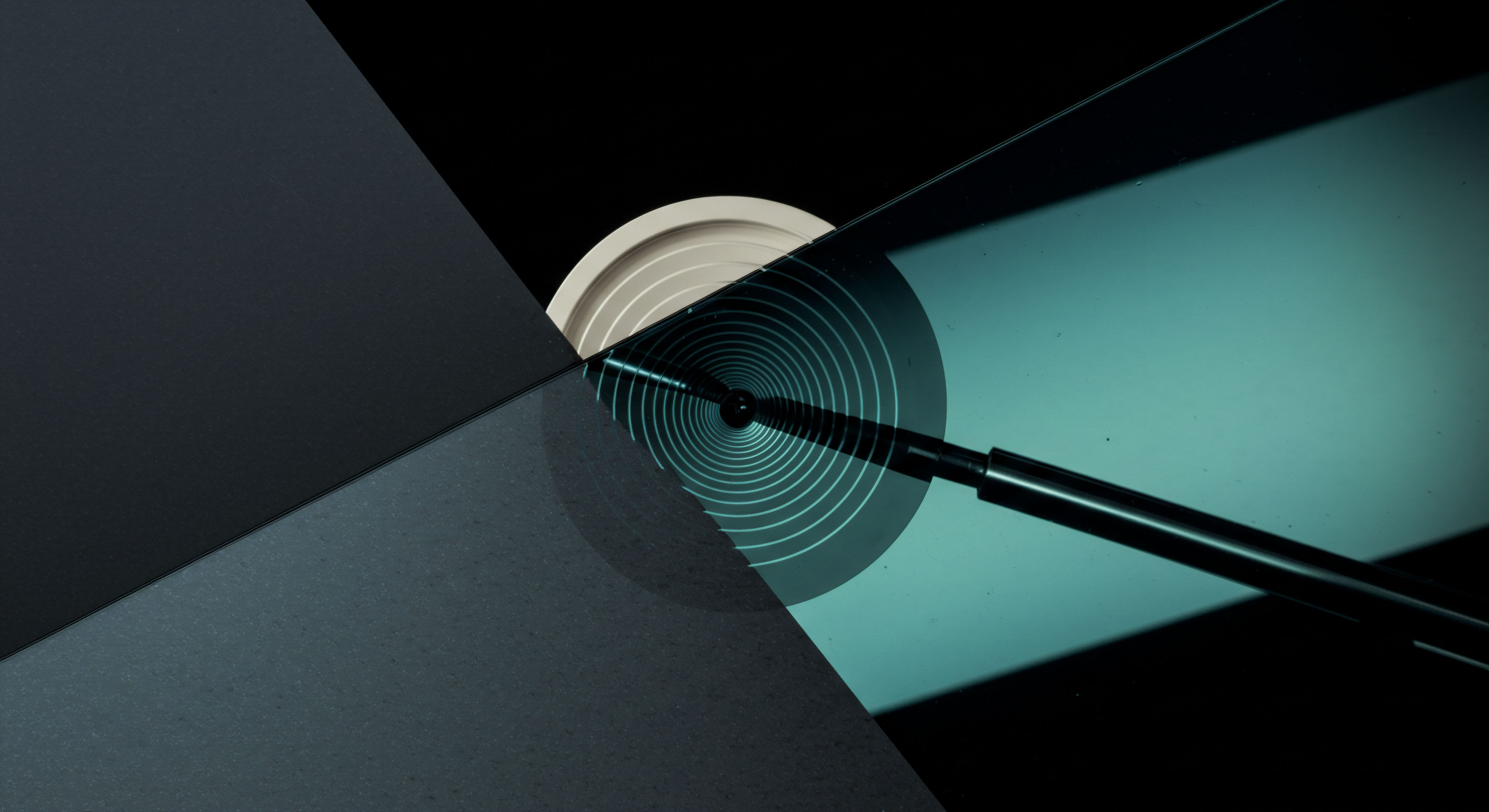 The composition reveals an interface suggesting a precision mechanism inherent in complex financial engineering like decentralized options protocols. Concentric cyan rings project outward from a central nexus, symbolizing potential strike price convergence or volatility skew mapping across a perpetual futures curve. Dark angular planes represent underlying asset market structure or collateral boundaries. A polished black stylus extends toward the center, evoking the precise execution required for automated market maker settlement or slippage minimization during a delta-neutral rebalancing event on a layer two solution. The pale circular element hints at locked margin or staked assets within a structured product, reflecting systemic risk parameterization beyond simple spot valuation. This visualization abstracts the iterative process of option Greeks management for synthetic asset generation.