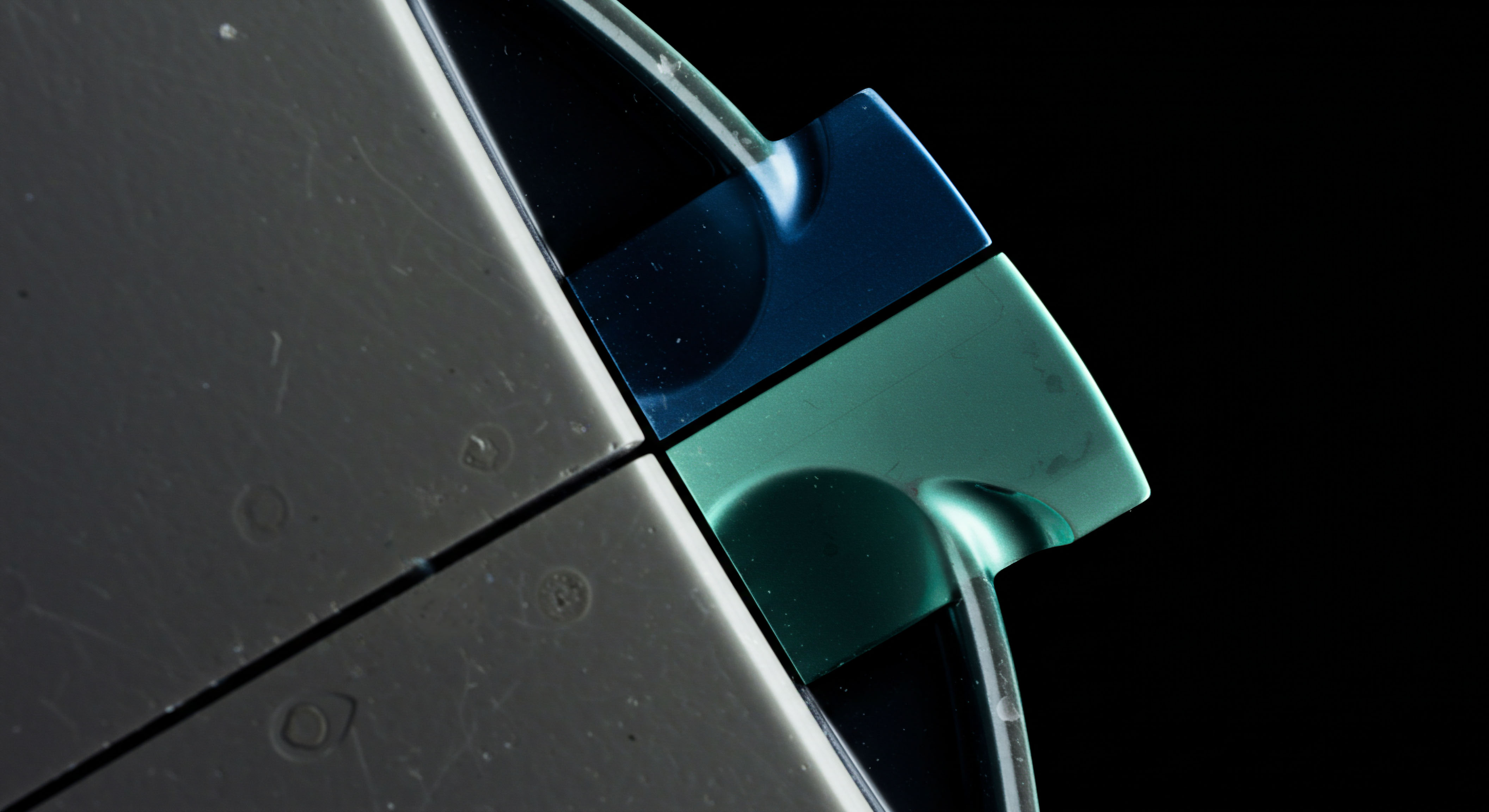 The visual depicts a sharp rectilinear interface dividing a matte grey substrate from a highly reflective quadrant exhibiting dichromatic iridescence, specifically deep cyan and teal reflections against pure black voids, evocative of systemic market fragmentation. This geometric tension mirrors the complex interplay of slippage inherent in high-frequency order book execution across decentralized finance protocols. The curved, polished surfaces suggest encapsulated liquidity pools or perhaps specialized hardware security modules HSM outputs under variable quantum entanglement stress. Such visual divergence implies non-linear price discovery mechanisms beyond standard Black Scholes models, touching upon stochastic volatility surfaces in novel derivative structures like perpetual futures contracts or embedded options within tokenized real-world assets TRWAs. The distinct color boundary emphasizes protocol segregation or hard forks in ledger consensus.