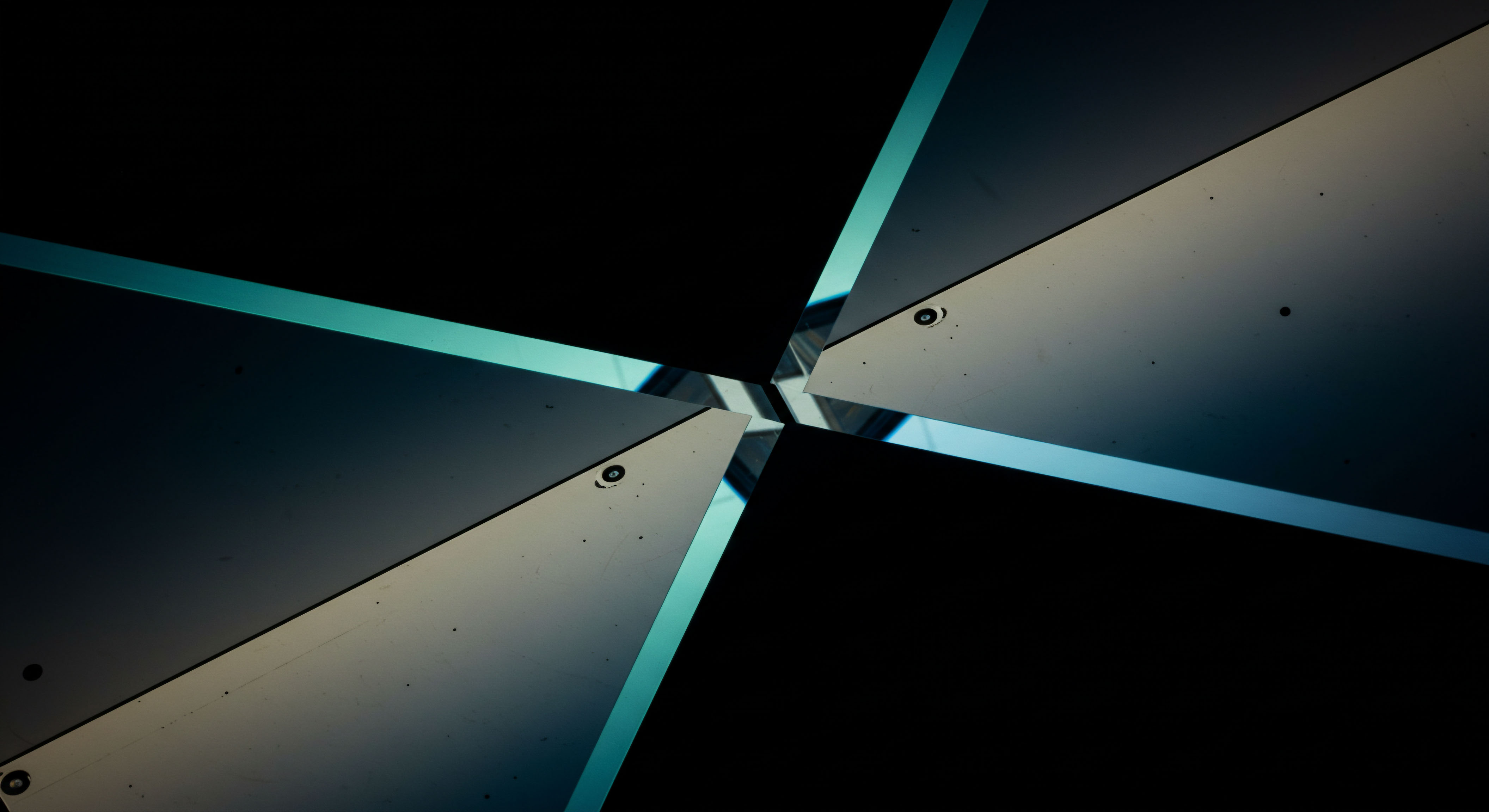 This visual composition depicts four dark, planar surfaces meeting at a central nexus, separated by thin, cyanic luminous apertures suggesting an intersection point. It embodies the structural geometry inherent in high-frequency options execution mechanisms within decentralized finance DeFi protocols. The slight imperfections and screw alignments hint at the physical constraints underlying immutable smart contract architecture controlling automated market maker AMM liquidity provisioning. This pattern mirrors the complex interplay of bid-ask spreads influencing synthetic asset settlement on perpetual futures exchanges, illustrating slippage reduction strategies via optimized order book depth. The converging lines represent the critical path to achieving instantaneous delta hedging in volatile token derivatives markets, embodying the efficiency frontier for non-custodial capital deployment and arbitrage opportunities across Layer 2 scaling solutions.