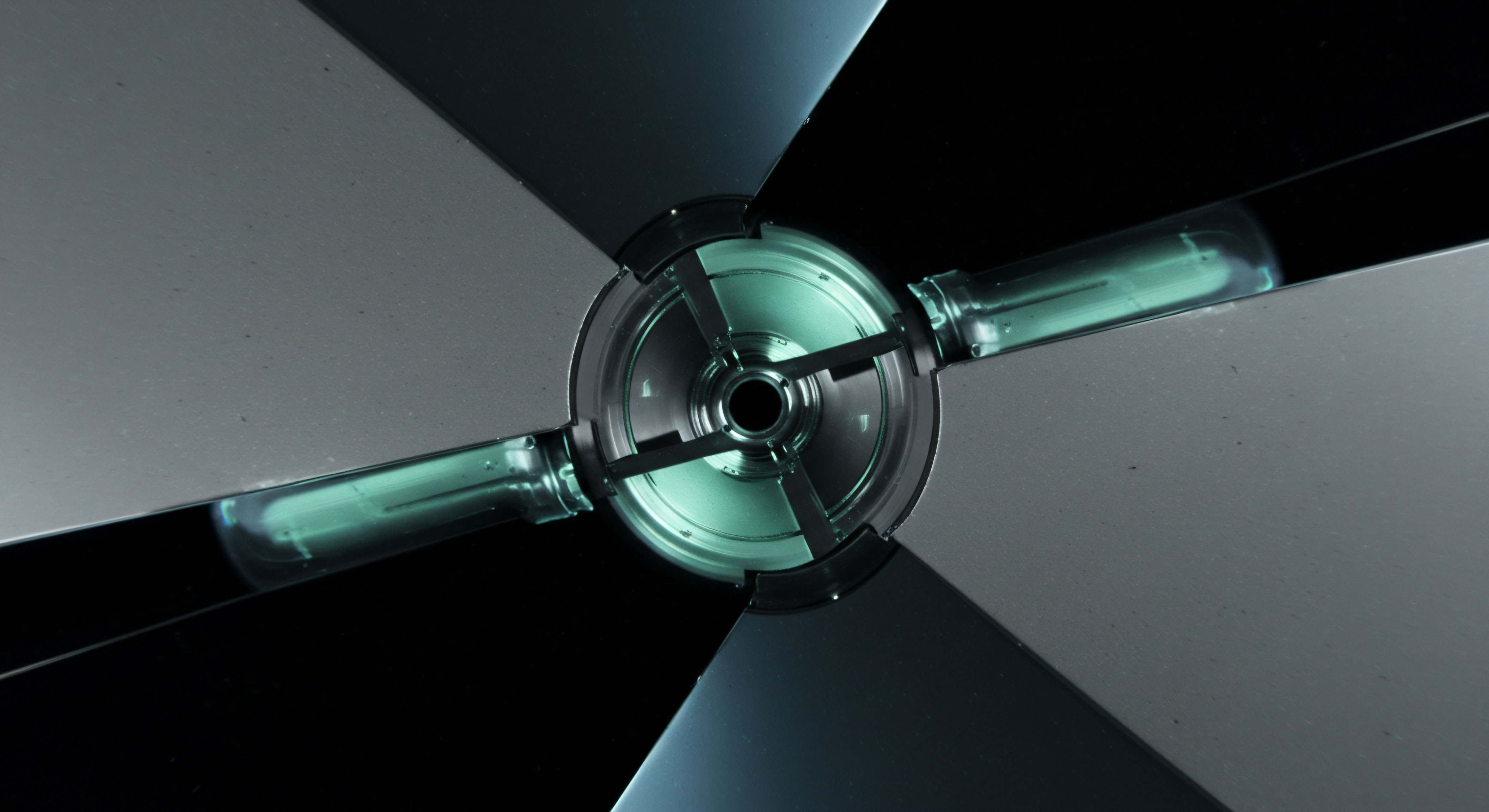 This abstract visualization depicts a central node resembling a sophisticated, four-bladed impeller or turbine mechanism against an abyss of deep black, illuminated by cool cyan light emanating from integrated linear energy conduits, suggesting intrinsic value flow. The metallic grey blades reflect a polished, low-friction surface, analogous to high-frequency trading execution environments or secure blockchain consensus validation apparatus. It embodies the complex mechanics of distributed ledger technology governance models, specifically mapping quadratic voting mechanisms or staking pool rotation dynamics. The illuminated tubes suggest constant data packet transmission or realized settlement layers, key components in on-chain derivatives settlement and impermanent loss mitigation strategies within DeFi liquidity provision protocols demanding robust oracle integration.