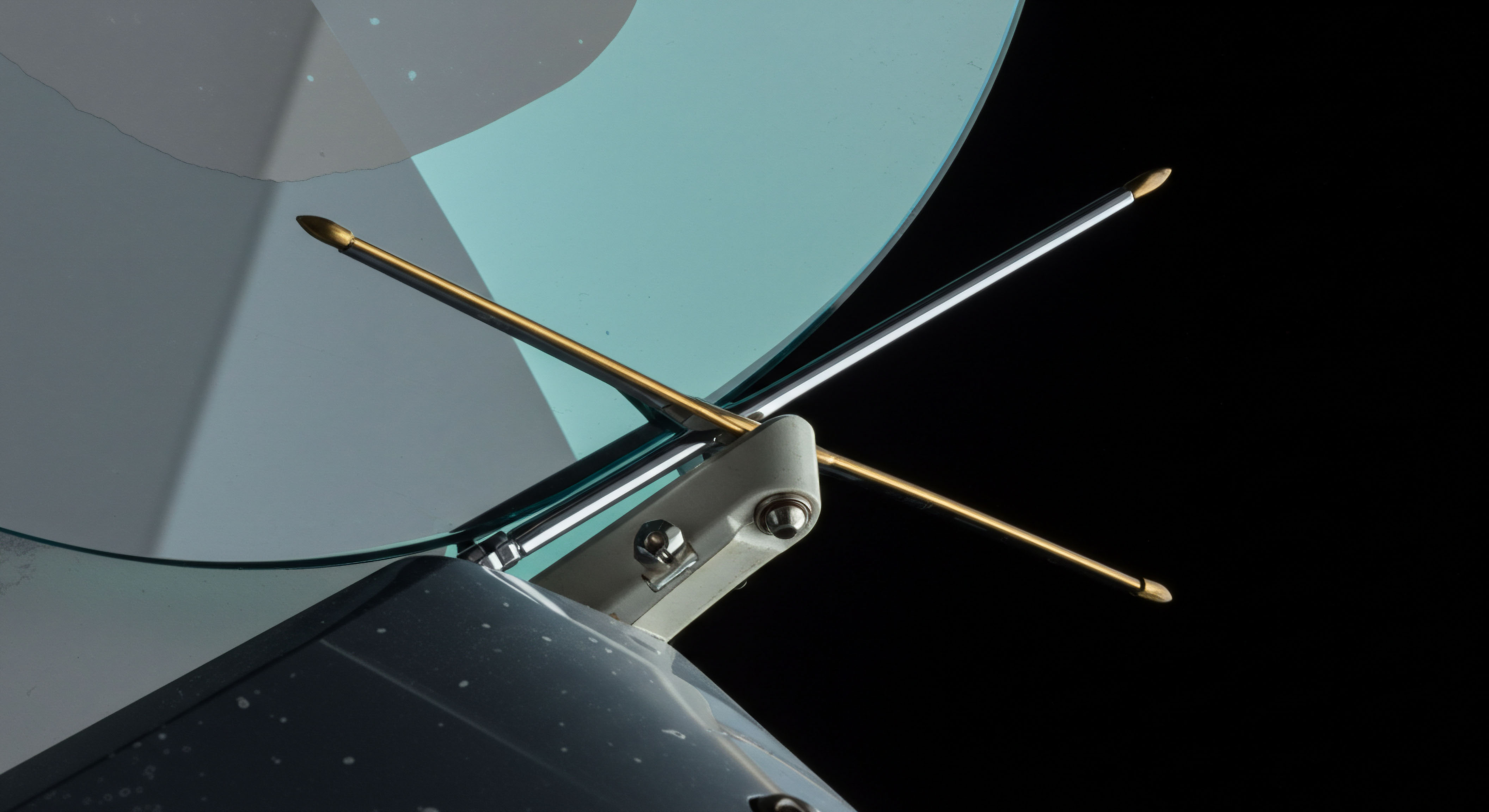 This close-up depicts the feedhorn mechanism of a communication or sensing apparatus, featuring crossed dipole antennas positioned against a subtly tinted, curved reflector surface against absolute blackness. The two telescoping antennae, one brass-hued and one silvered, project outward from a central mounting block, emblematic of directional signal acquisition or transmission. This precise orthogonal alignment mirrors the structure needed for synthesizing complex derivative products like spread strategies or synthetic short positions on a decentralized exchange platform. The sharp tips suggest focused energy vectors, conceptually linking to precise strike price targeting in options contracts or efficient execution in dark pool liquidity sourcing for large crypto arbitrage maneuvers, reflecting robust decentralized finance infrastructure architecture.