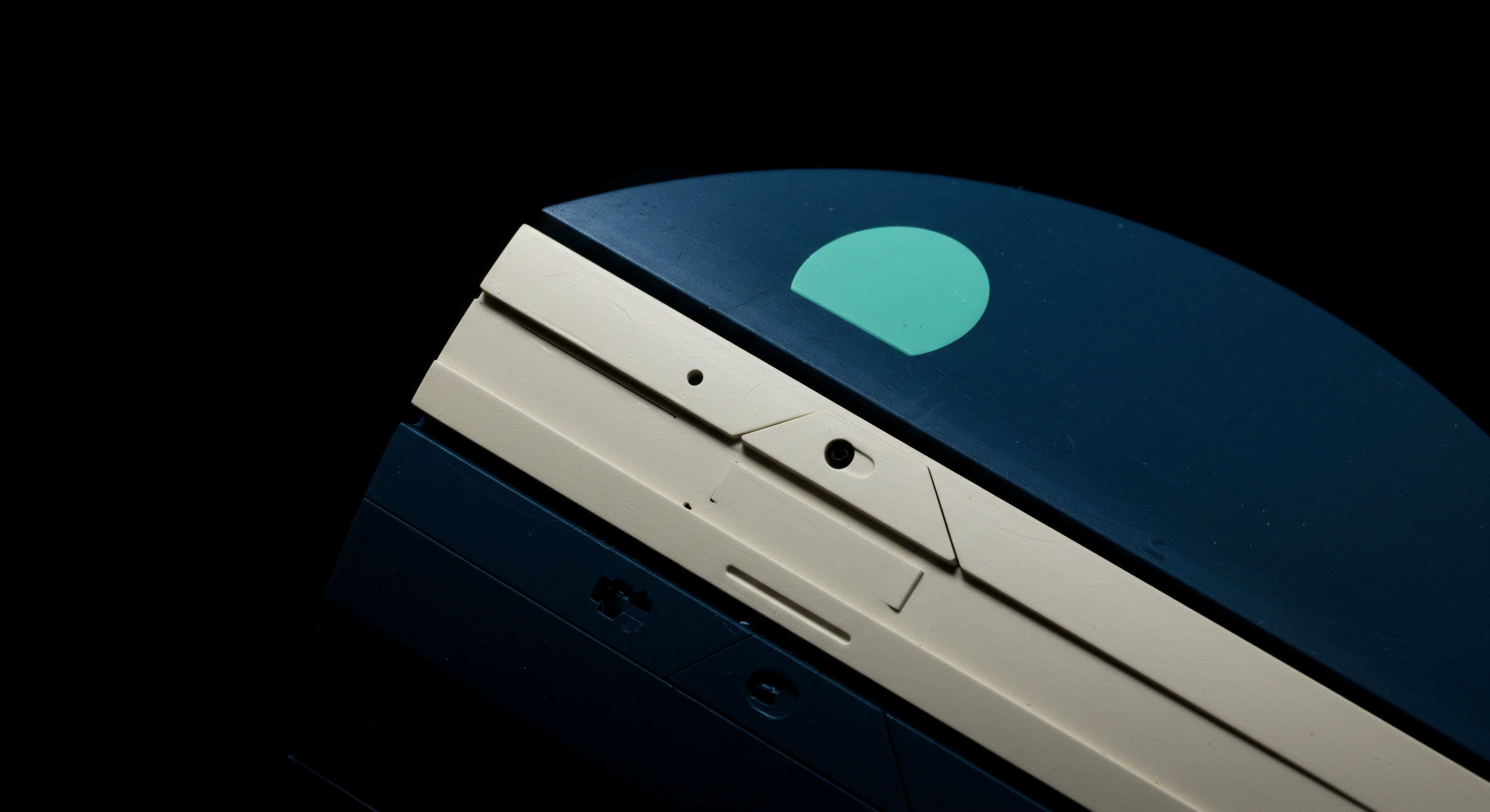 This close up reveals a dark navy substrate juxtaposed against a matte beige housing indicative of robust hardware security modules or cold storage apparatus. A subtle aqua semicircle suggests a graphical representation of on chain progress or collateralization ratio within decentralized finance. Small apertures hint at physical key audit points or tamper-evident seals essential for securing digital asset private keys and managing derivatives exposure. The precise geometry speaks to engineering rigor required for high security cryptographic operations and managing futures contract margin calls. This aesthetic symbolizes the tangible interface layer underpinning secure ledger transactions and the critical infra required for decentralized autonomous organizations governance tokens.