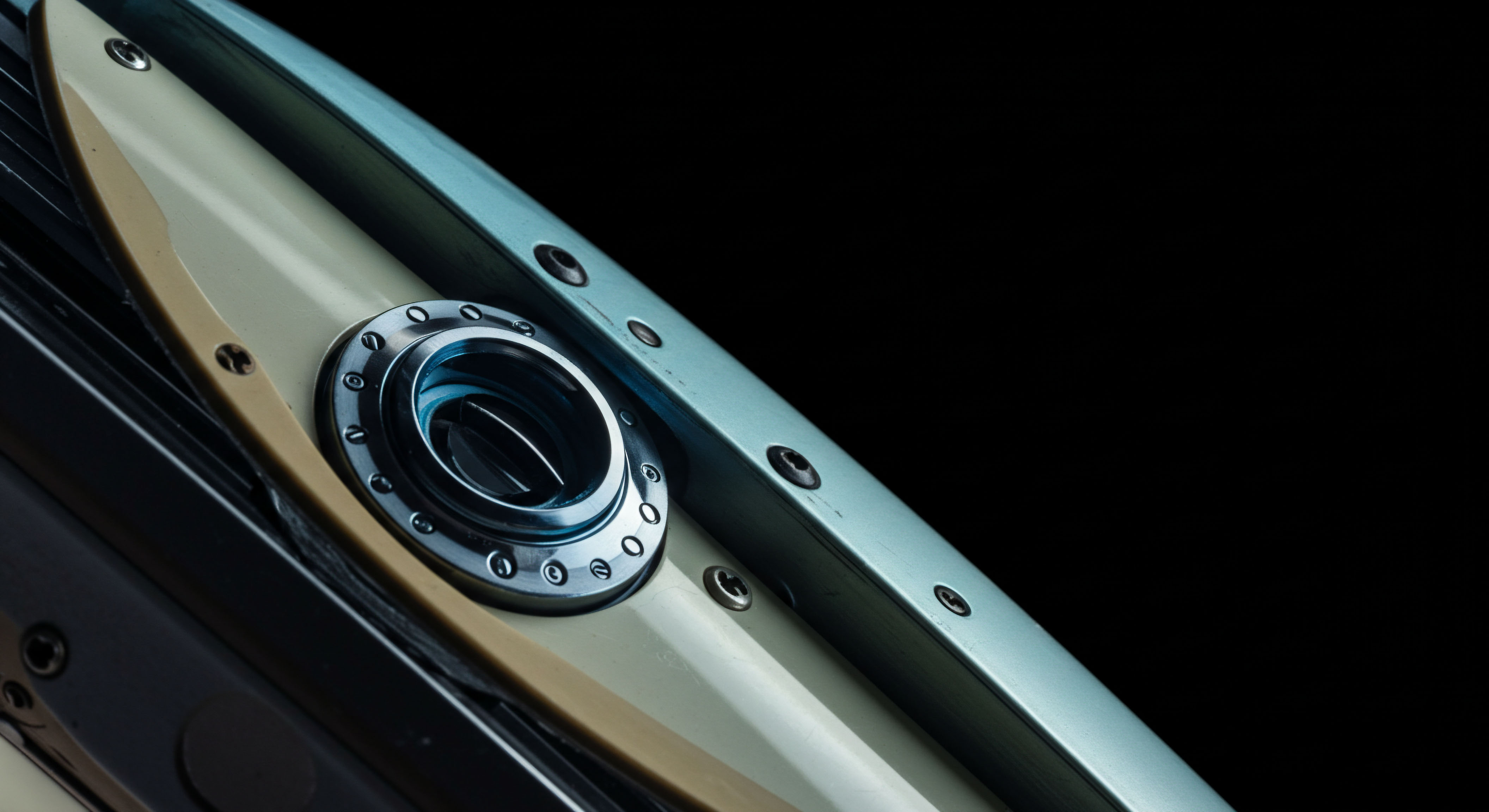 This close-up features polished metallic hardware surrounding a recessed aperture set within layered substrates of cream and pale cyan composite materials, evoking a sealed system interface. This visual metaphor suggests the robust security underpinning decentralized finance protocols and the layered complexity of on-chain governance mechanisms. The precise metallic fixture, secured by small fasteners, represents the immutable smart contract logic safeguarding digital asset custody, akin to securing collateral in a collateralized debt position or escrow within an over-the-counter derivatives execution. The interplay of materials hints at the physical manifestation required for cold storage key security or hardware security modules protecting private keys essential for managing high-value decentralized autonomous organization treasuries and navigating complex delta hedging strategies inherent in perpetual futures markets. This texture embodies resilient infrastructure required for regulatory compliance in tokenized securities.