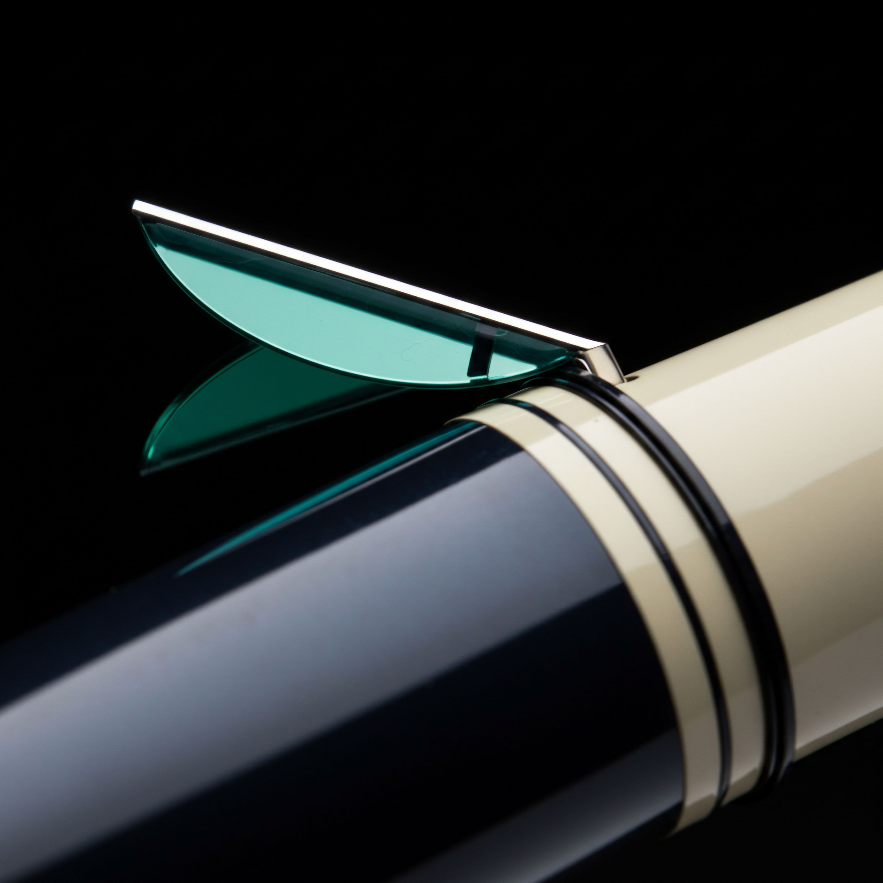 This macro photograph isolates a high-gloss writing instrument component featuring a distinctive teal-hued, metallic clip cantilevered over deep indigo and cream acrylic barrels. The clip's aerodynamic, sweeping profile mirrors the implied trajectory of synthetic option pricing curves, specifically evoking an in-the-money long call structure nearing expiration. The polished surfaces reflect a sharp subsurface projection, symbolizing the immediate transparency of a decentralized exchange order book depth. This aesthetic resonates with the disciplined execution required for high-frequency arbitrage across fragmented cross-chain liquidity provisions. The structural division between the dark and light resins represents the bifurcation of on-chain settlement versus off-chain custodian risk in structured crypto products like synthetic future contracts or tokenized real-world assets.