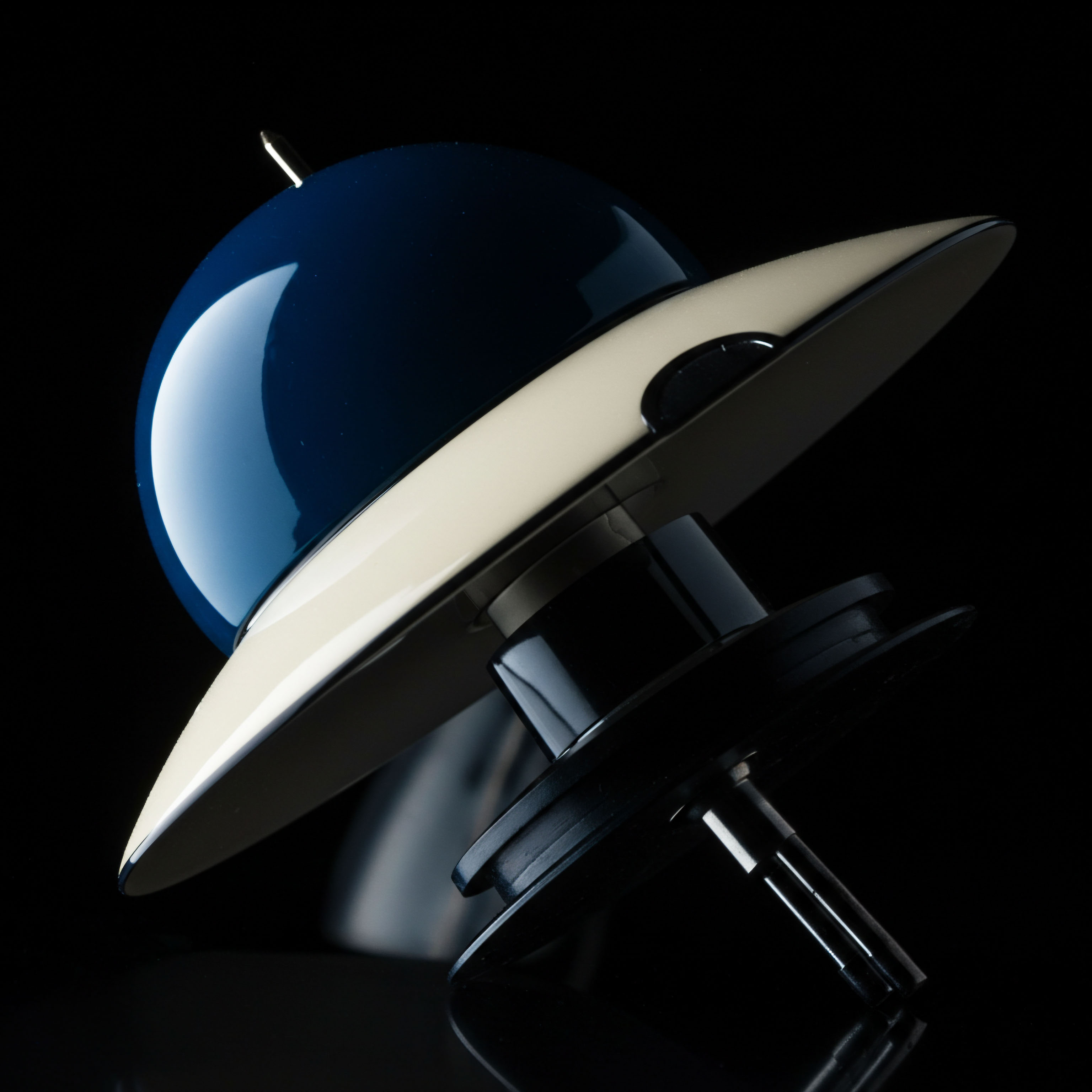 This striking visual depicts a highly stylized, streamlined object, reminiscent of a retro-futuristic Unidentified Flying Object, featuring a dominant high-gloss navy dome atop an ivory-colored saucer section, contrasted against a deep black background creating dramatic chiaroscuro. The central, dark spindle mechanism suggests intricate mechanical underpinnings, symbolizing the complex smart contract logic driving robust Layer 2 scaling solutions or novel Automated Market Maker designs. The dynamic tilt implies rapid ascent or volatile trajectory, mirroring aggressive yield farming strategies or unexpected liquidity shifts within decentralized autonomous organizations DAO governance structures. This aesthetic evokes the elegant yet opaque operational layer of permissionless systems, where robust security primitives undergird novel derivative instruments like perpetual swaps or options vaults, focusing on transparent execution amidst underlying systemic opacity.