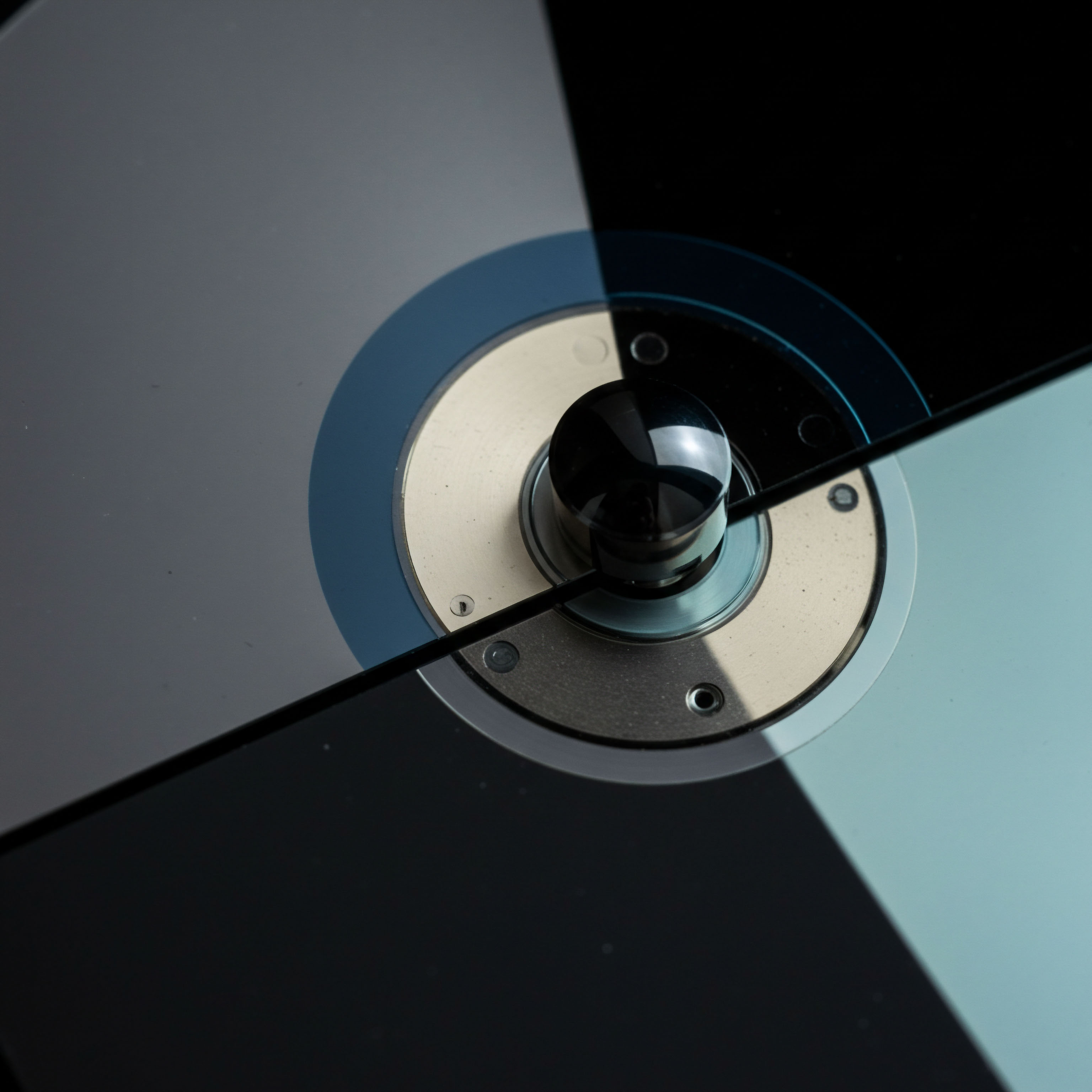 The highly polished metallic substrate secured by visible fasteners centers this composition, suggestive of a secure cryptographic settlement layer or a high-frequency trading engine's core component. Two intersecting planes of varying translucency, one dark matte and the other subtly luminous blue-gray, partition the visual field, symbolizing bifurcated market states or leveraged derivatives exposure across dark pool liquidity venues. This abstract visual dichotomy mirrors the intrinsic risk management required in decentralized finance governance structures managing complex synthetic asset mechanisms like perpetual swaps or path-dependent exotic options. The central black knob suggests a critical control point or a cryptographic key management interface, vital for maintaining atomic settlement finality in volatile digital asset ecosystems where slippage and counterparty risk are primary concerns for sophisticated market makers dealing with basis trading strategies.